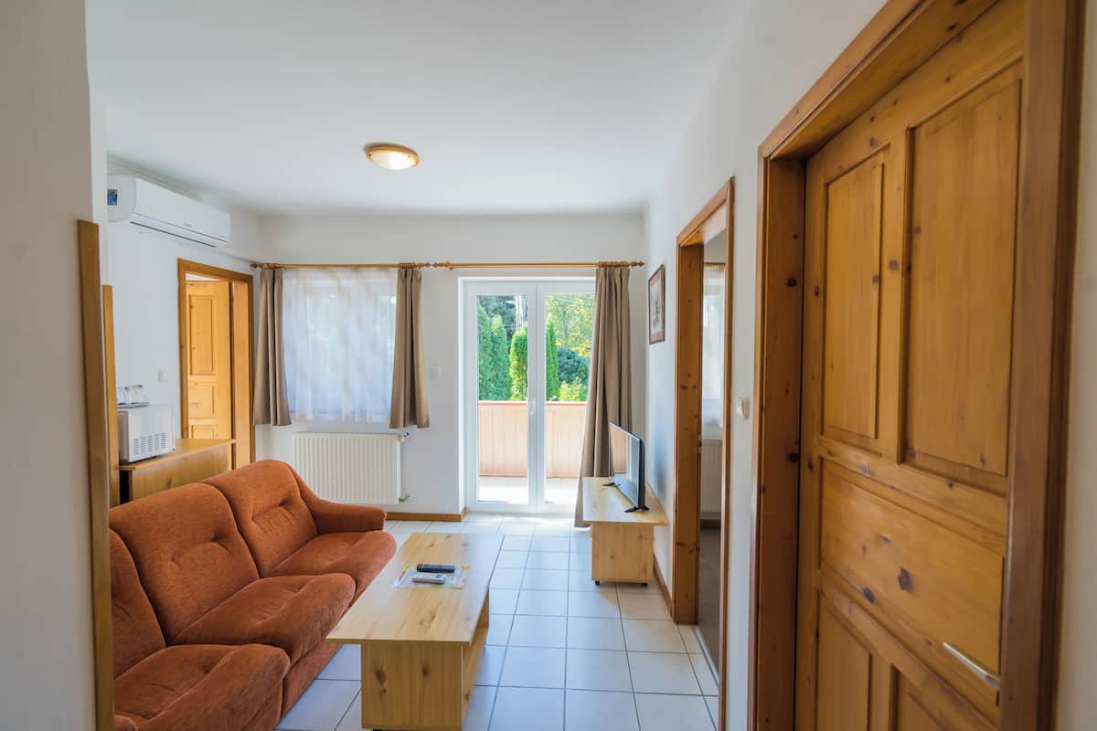 A living room with a sofa, a coffee table, a TV on a stand, and a wooden door.