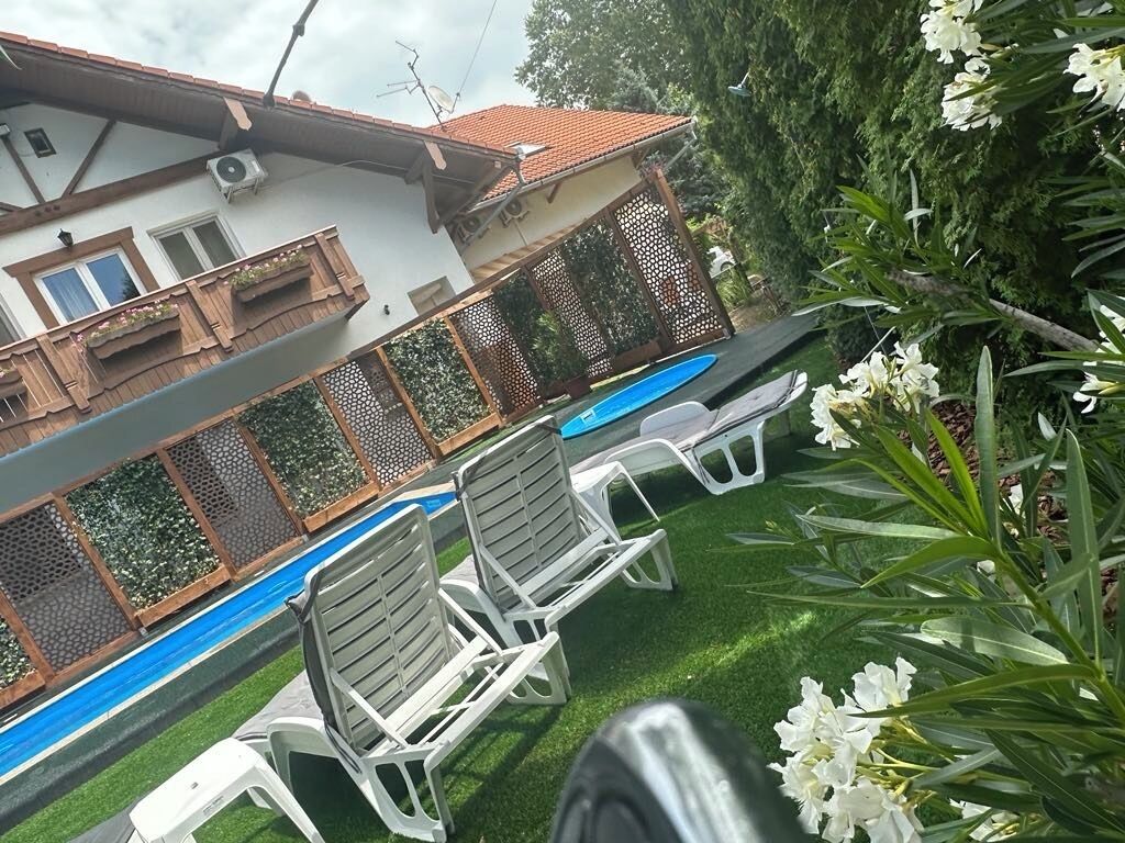 A pool area with white lounge chairs and a blue pool.