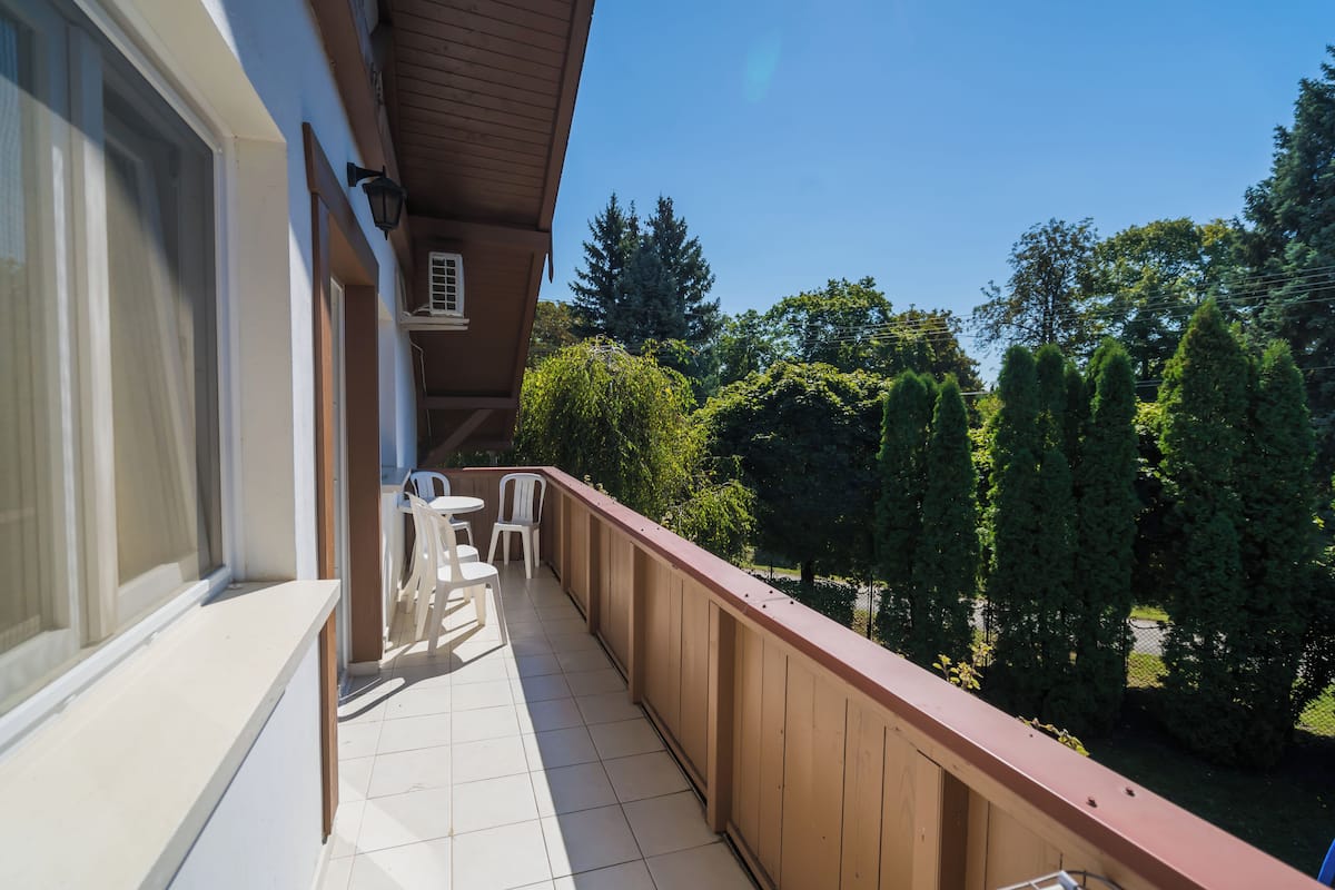 A balcony with a wooden railing, white chairs, and a small table.