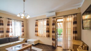 A living room with a sofa, a coffee table, and a small table. There is a sliding glass door with curtains. - Sommer Pension (Balatonfoldvar)