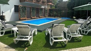A swimming pool with lounge chairs, a house with a balcony, and a green fence. - Sommer Pension (Balatonfoldvar)