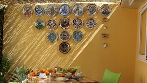 Zona de menjador amb una taula preparada per esmorzar, amb diverses fruites i una selecció de plats i cuplets.