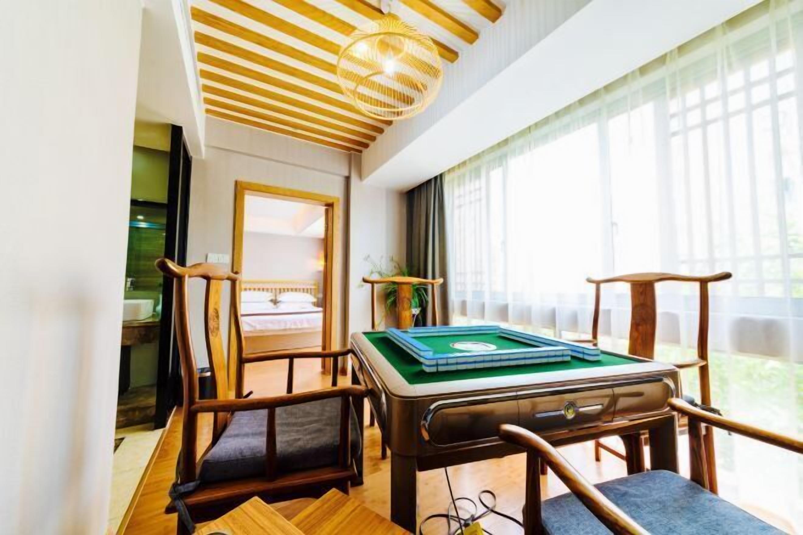 A cozy room with a pool table, wooden chairs, and a large window providing natural light.