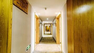 A hotel corridor with wooden doors, a carpeted floor, and a sign on the wall.