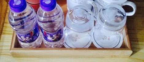 A wooden tray with two water bottles, a teapot, and a cup.