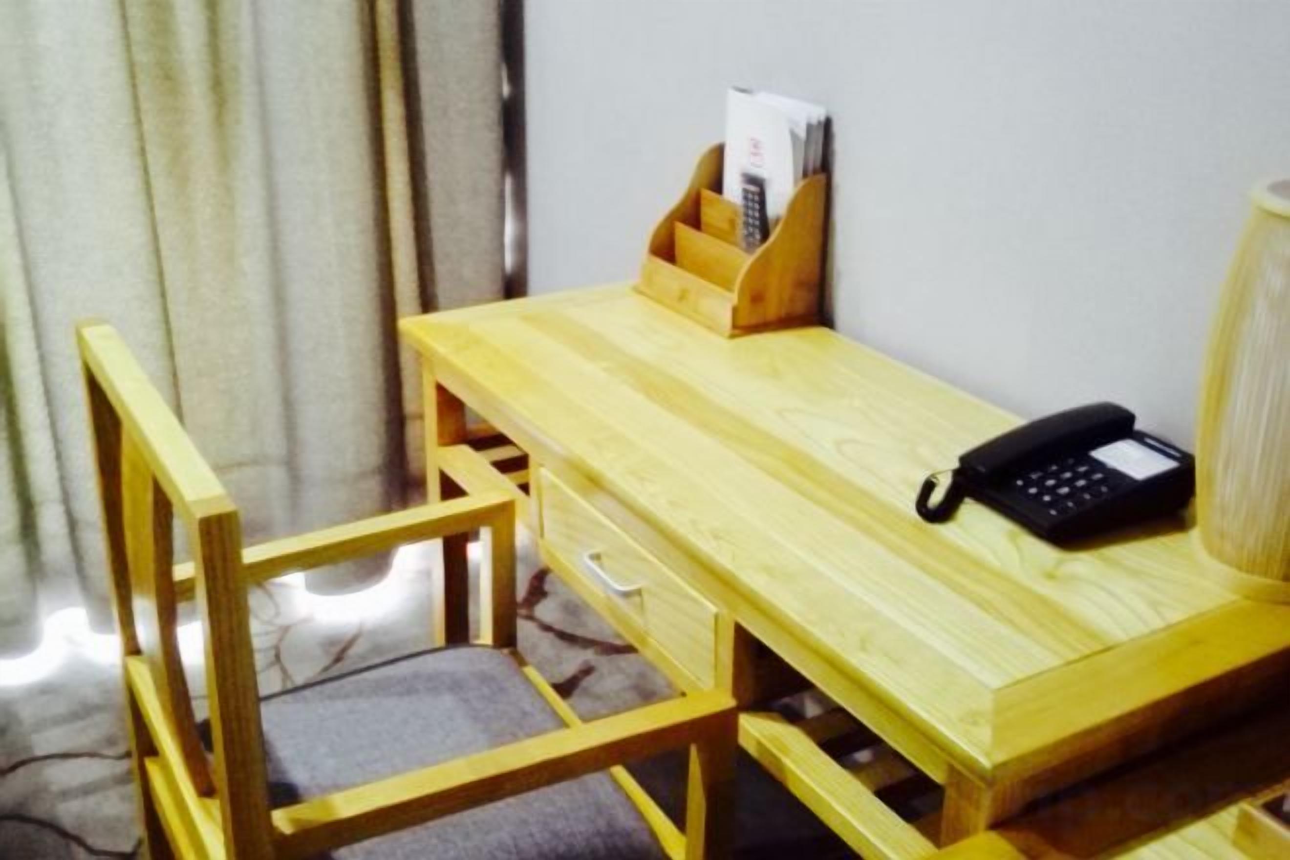 A wooden desk with a telephone, a chair, and a magazine holder.