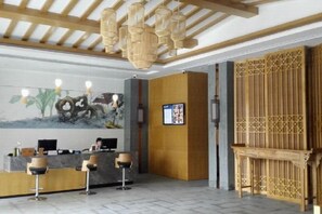 Un espace d’accueil comprenant un comptoir de réception en bois, un ordinateur et un coin salon avec des chaises.