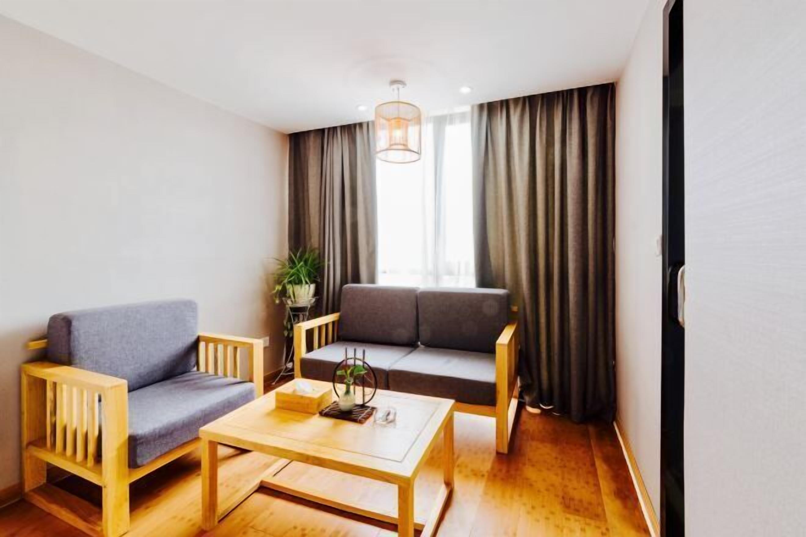 A room with a sofa, a chair, a coffee table, and a plant.