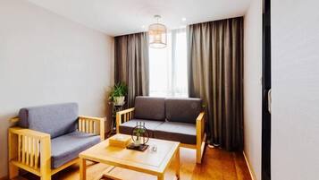A room with a sofa, a chair, a coffee table, and a plant.
