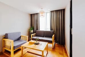 A room with a sofa, a chair, a coffee table, and a plant. - Xiao Jing Hotel (Anji)
