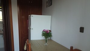 Un comedor con una mesa cubierta por un mantel de lunares, sillas de madera y un jarrón con flores.