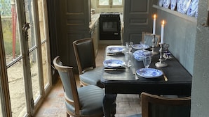 Een eethoek met een tafel voor vier personen, stoelen, een fornuis en een plank met borden.