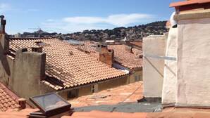 A rooftop with terracotta tiles, a satellite dish, and a view of a hilly townscape. - Apartment @typique (Vieux Port) (La Ciotat)