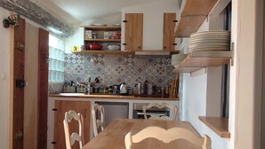 A kitchen with wooden cabinets, a tiled backsplash, and a dining table with chairs. - Apartment @typique (Vieux Port) (La Ciotat)