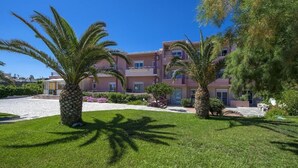 A multi-story hotel with a well-maintained lawn and palm trees. - SEA SIDE (Chania)