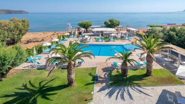 A pool area with lounge chairs, palm trees, and a view of the sea. - SEA SIDE (Chania)