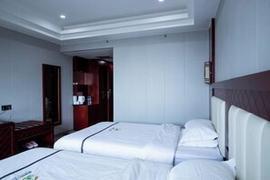 Habitación de hotel con dos camas, un cabecero de madera, un escritorio pequeño y un armario.