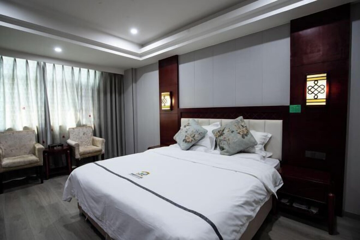 A hotel room with a large bed, two armchairs, a small table, and a nightstand.