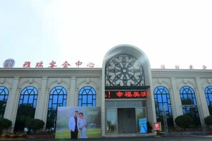 A building with a large arched entrance, a prominent sign with Chinese characters, and a large poster on the facade. - Yarui Holiday Garden Hotel (Guangshui)