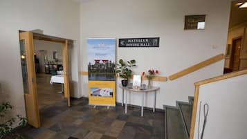 Un vestíbulo de hotel con un cartel del Comedor Matsalur, un letrero de bienvenida y un anuncio que promociona el hotel como un destino de verano.