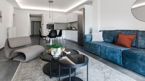 A modern living room with a blue sofa, a round coffee table, and a grey bench. - Stellar 3BR Apartment with Balcony (Palaio Faliro)