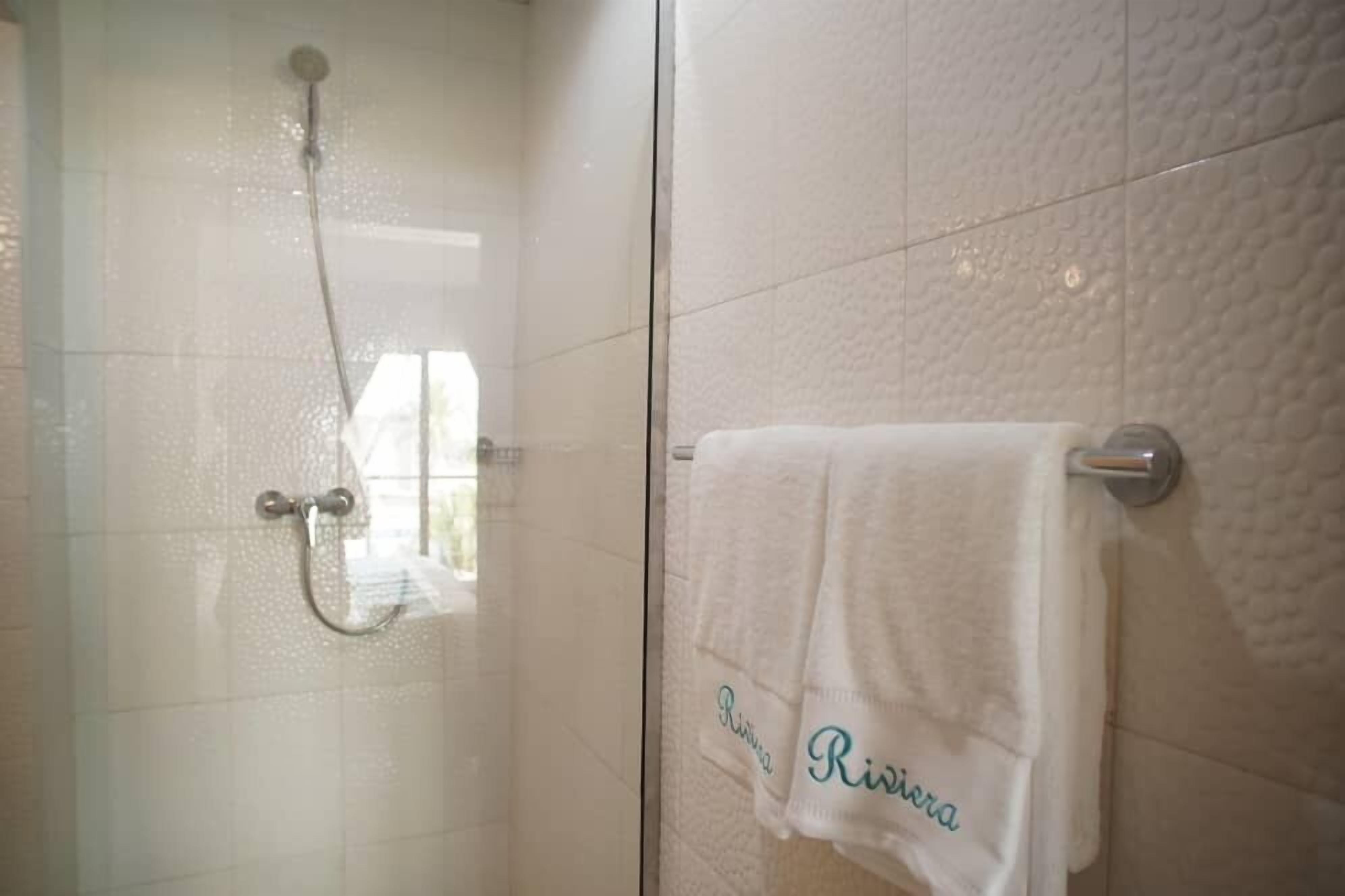 A bathroom with a glass shower enclosure, a towel rack with a white towel, and a textured wall.