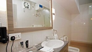 A hotel bathroom with a large mirror, a sink, a toilet, and a shower area. - Riviera Suites (Lagos)