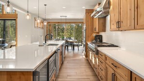 Una cocina moderna con armarios de madera, una isla grande y un comedor con vistas al exterior.