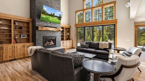 Un salón amplio con chimenea, ventanas grandes y un rincón de descanso acogedor.