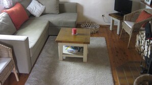 Ein Wohnzimmer mit einer Couch, einem Couchtisch, einem Fernseher und einem Korbsessel.