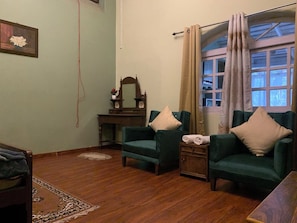 A cozy living room with two green armchairs, a wooden side table, a small wooden cabinet, and a mirror on a dresser. - Rose Villa British Colonial Heritage Bungalow, Takdah (Takdah)
