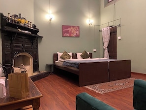 A cozy room with a bed, a fireplace, a rug, and a table with a bag. - Rose Villa British Colonial Heritage Bungalow, Takdah (Takdah)