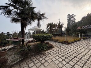 A garden with a gazebo, palm trees, and a paved walkway. - Rose Villa British Colonial Heritage Bungalow, Takdah (Takdah)