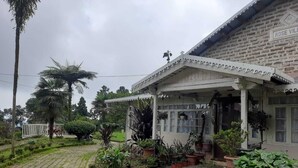 Una casa tradicional con un porche, rodeada de exuberante vegetación y un camino pavimentado.