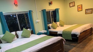A hotel room with two wooden beds, teal curtains, and a view of trees through the windows. - Rose Villa British Colonial Heritage Bungalow, Takdah (Takdah)