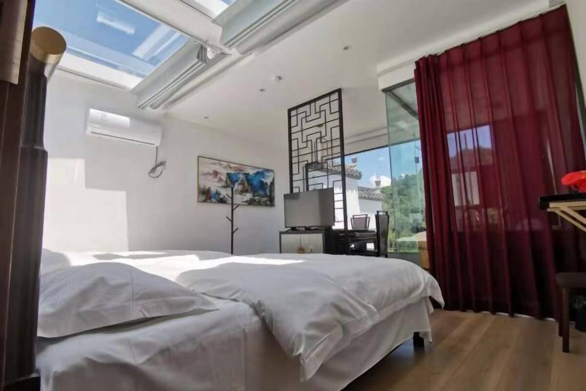 Une chambre à coucher avec un lit, un bureau, une chaise, une télévision et un tableau.