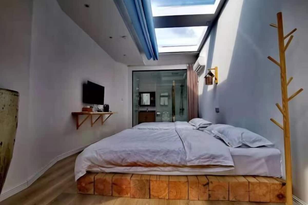 Relax in a serene bedroom with a skylight above the bed, a flat-screen TV, and a convenient shelf.
