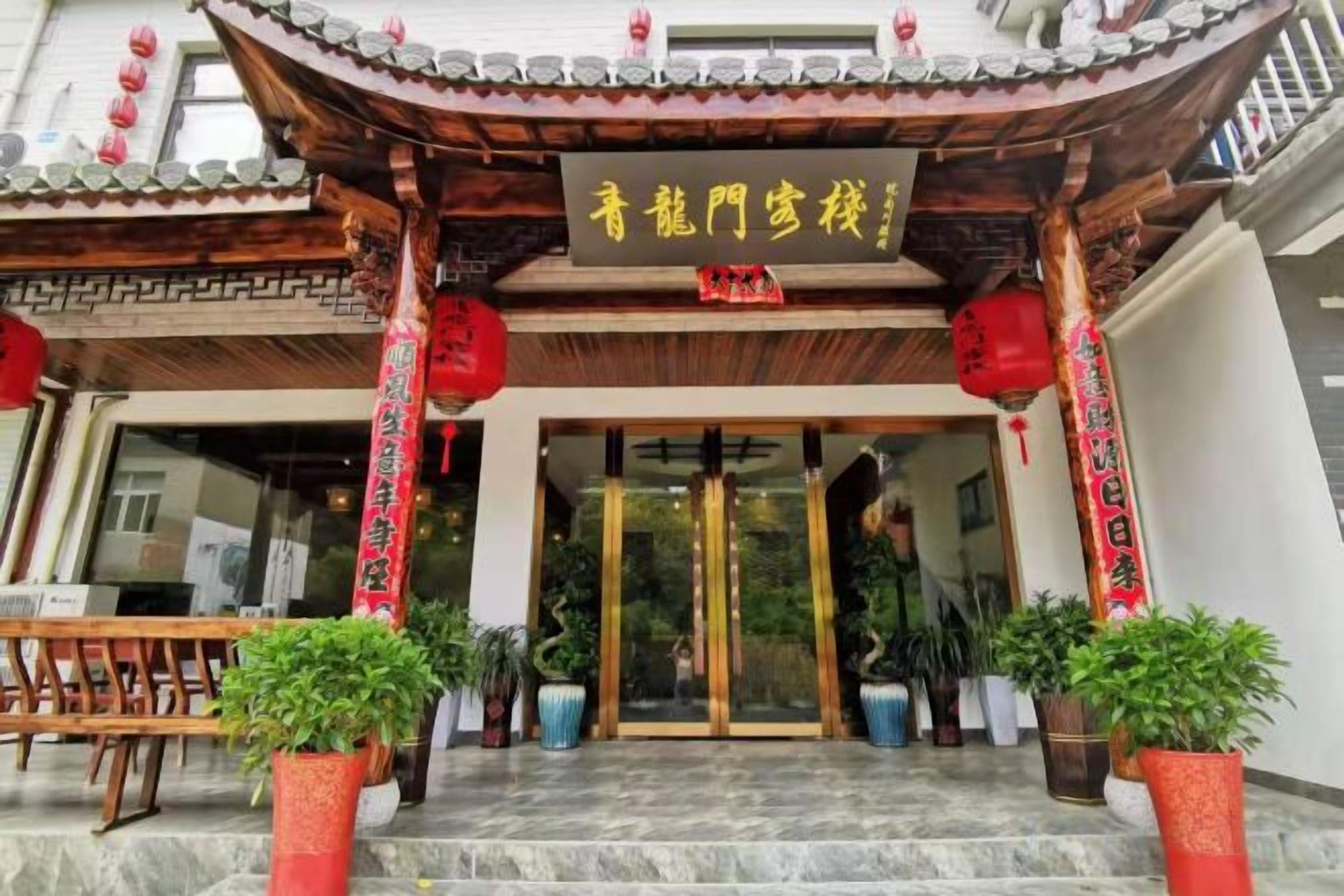 A traditional Chinese building entrance with a tiled roof, red lanterns, and potted plants.