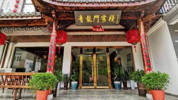 A traditional Chinese building entrance with a tiled roof, red lanterns, and potted plants.