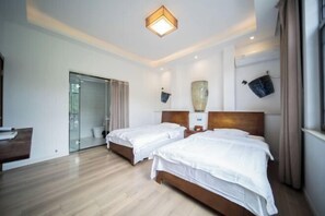 A hotel room with two beds, a wooden floor, a glass door leading to a bathroom, and a ceiling light fixture. - Ningguo Qinglongmen Inn (Ningguo)