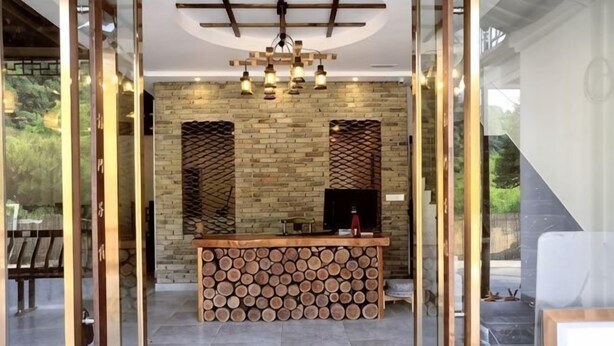 A reception area with a wooden log bench, a TV, and a brick wall with a geometric pattern.