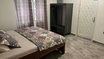 A bedroom with a bed, curtains, a wardrobe, and a door.