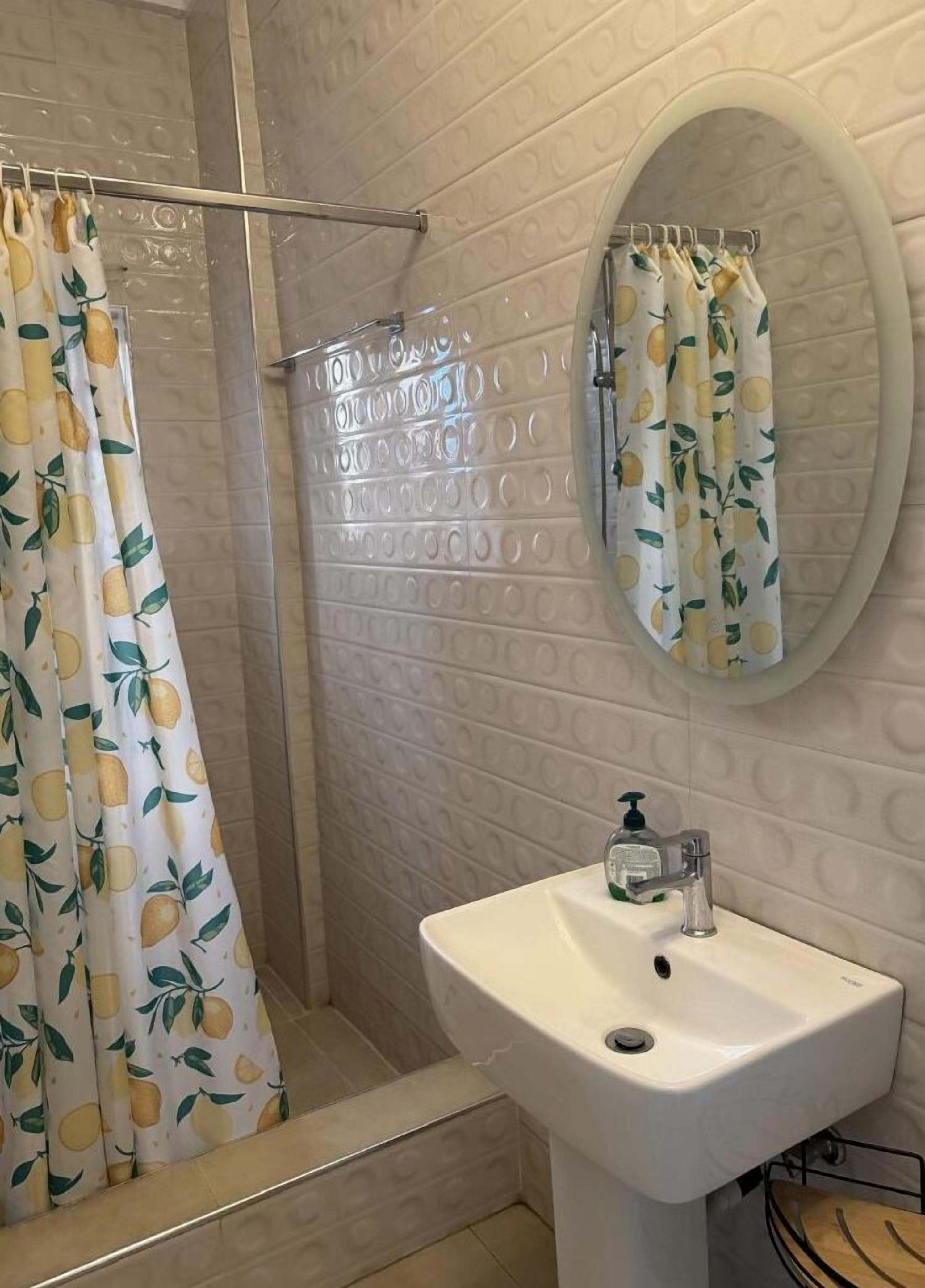 A bathroom with a shower, a sink, and a mirror.
