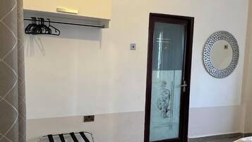 A room with a tiled floor, a bench, a coat rack, a door with a glass panel, and a decorative mirror.