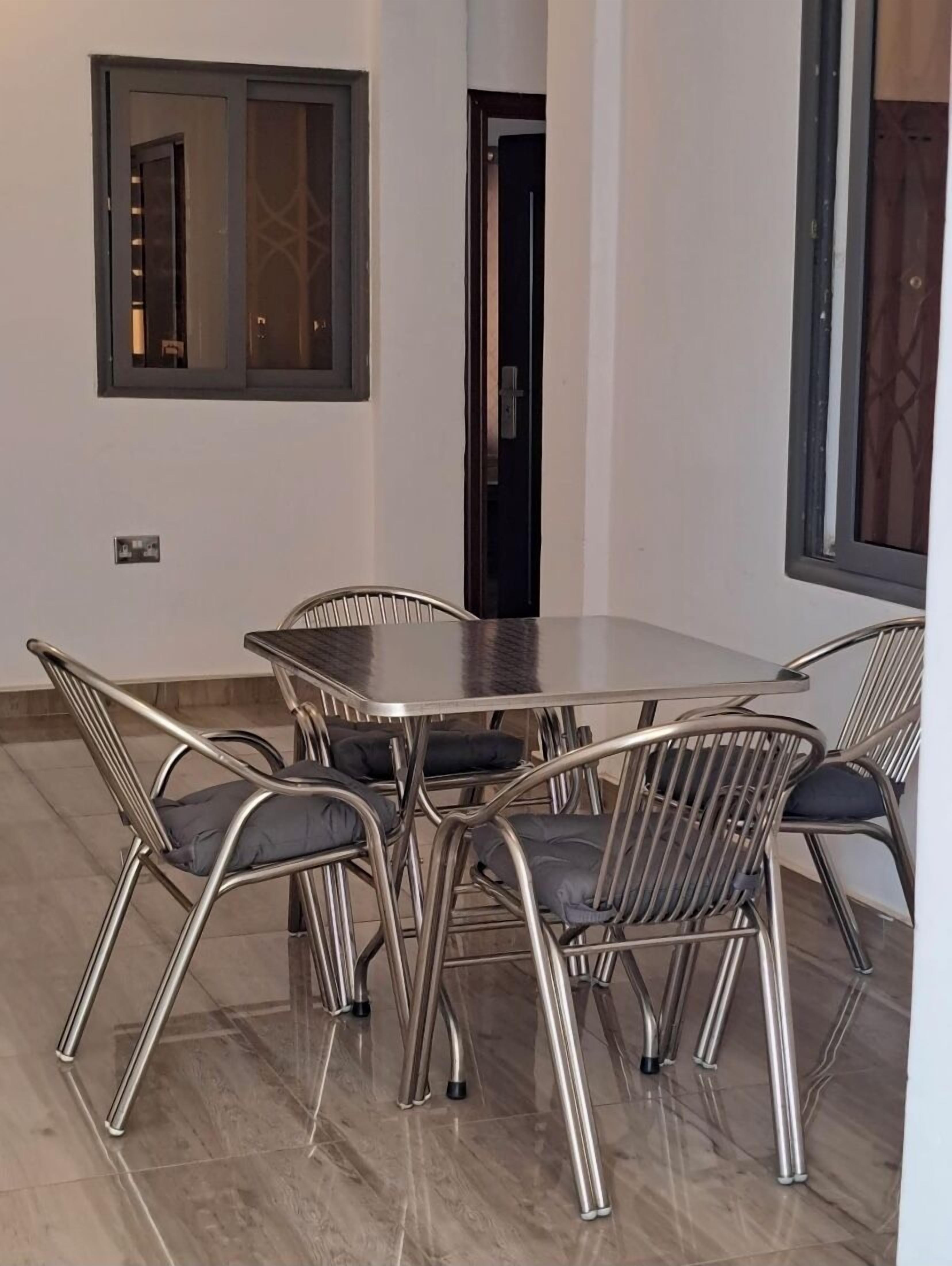 A dining area with a rectangular table and six metal chairs with cushions.
