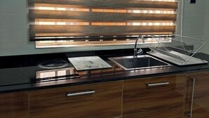 A kitchen with a black countertop, stainless steel sink, and wooden cabinets. - BAFFOUR APARTMENTS (Kumasi)
