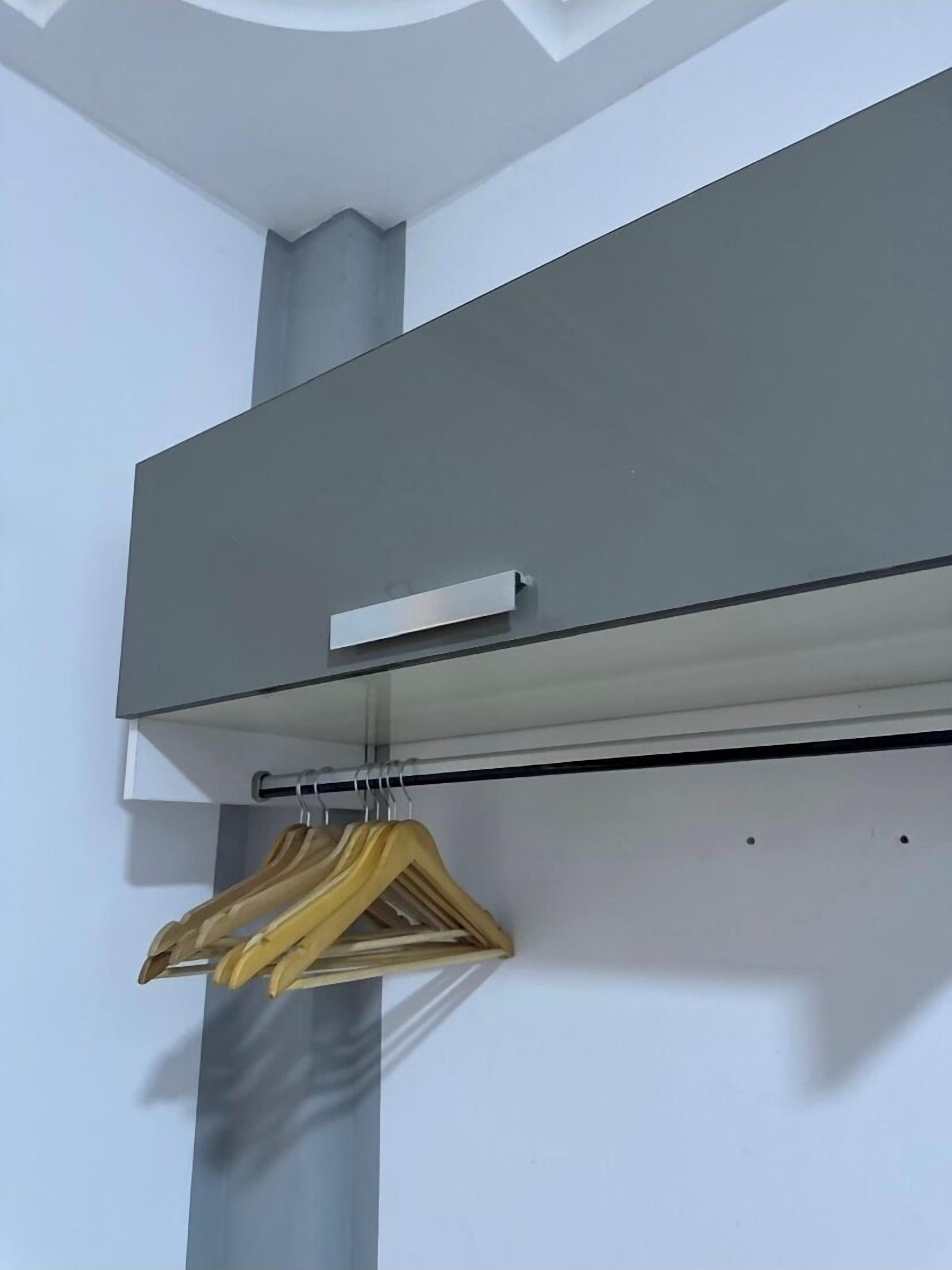 A modern, minimalist room with a grey wardrobe and a hanging rack with clothes.