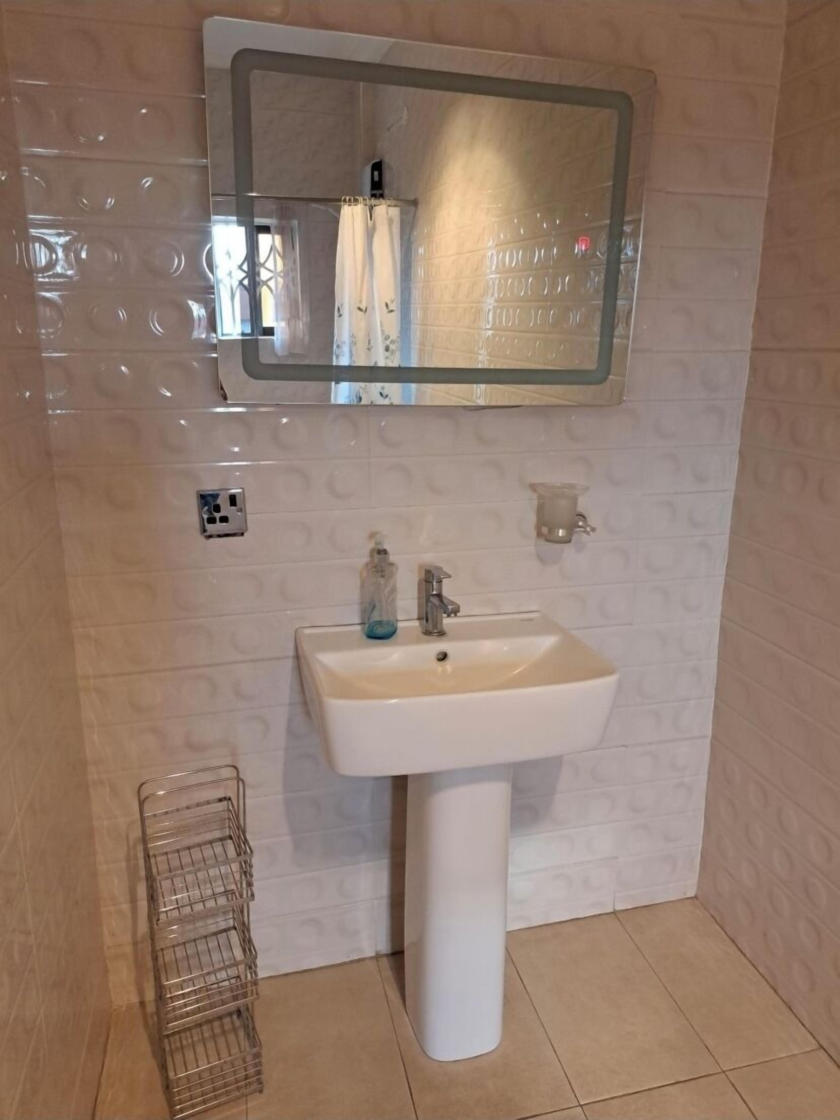 Un baño con lavamanos blanco, un espejo y una cortina de ducha.
