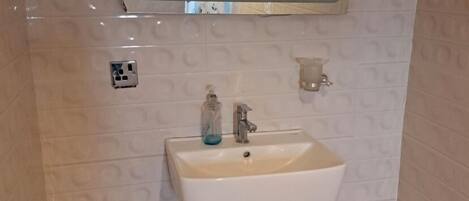 Un baño con lavamanos blanco, un espejo y una cortina de ducha.