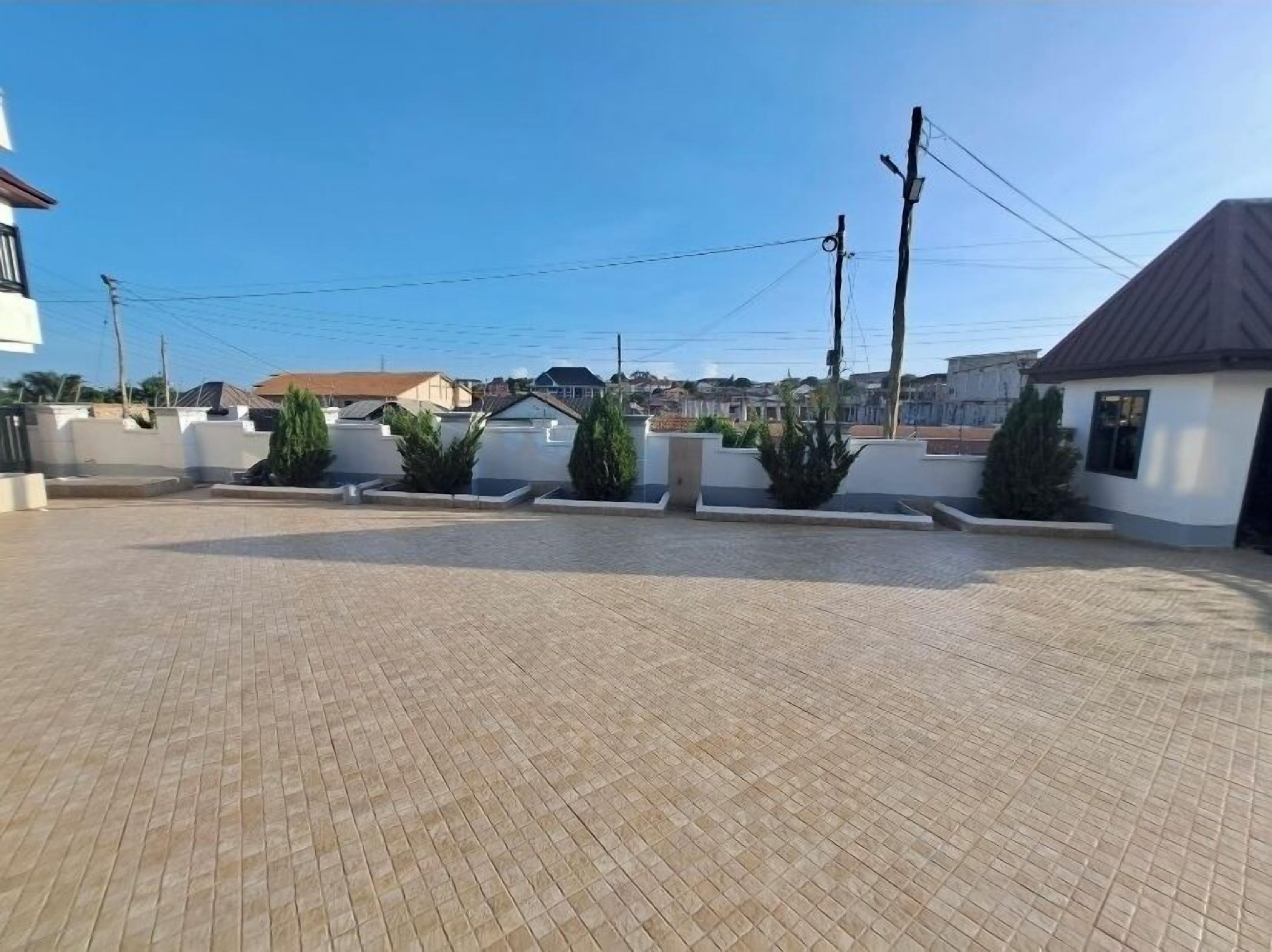 A paved outdoor area with a clear sky, surrounded by buildings and utility poles.